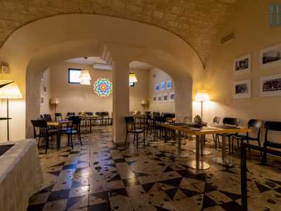 Ci spostiamo nei due vani laterali, che adesso ospitano i tanti tavoli del caff�. Quello di destra, leggermente rialzato, presenta lo stesso pavimento del precedente ed � diviso da una doppia arcata bianca, sorretta da una possente colonna